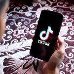 Hand holding phone showing TikTok logo