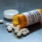 Open pill bottle with white tablets spilled out