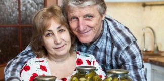 Older couple smiling with jars of pickles