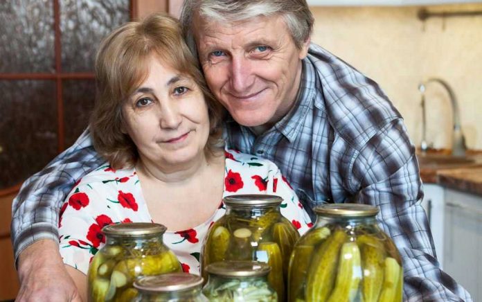 609985676 Older couple smiling with jars of pickles