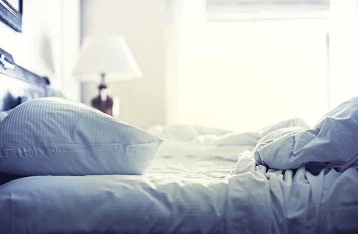 shutterstock_197128130.jpg A cozy unmade bed with soft pillows and bedding in a lit room