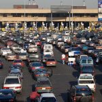A crowded parking lot filled with cars near a border crossing