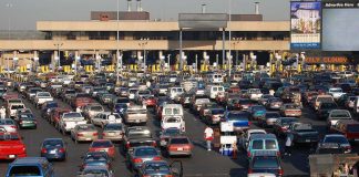 A crowded parking lot filled with cars near a border crossing