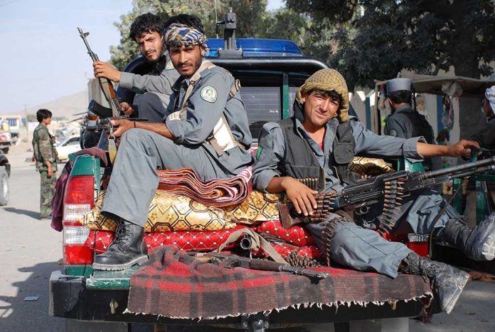 shutterstock_8768389.jpg Three armed soldiers sitting on the back of a military vehicle in an urban setting