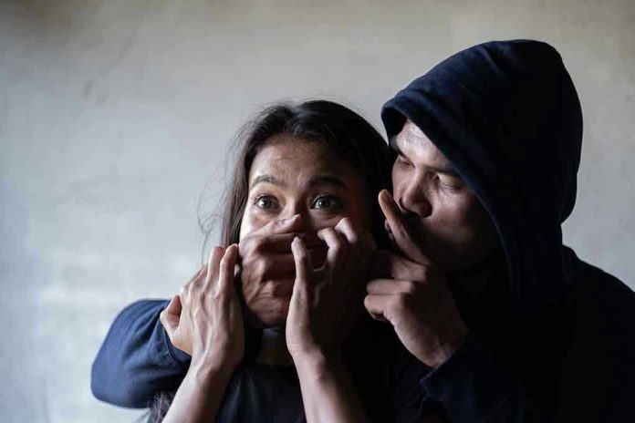 Man holding woman's mouth, gesturing silence.