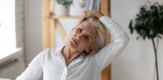 Woman stretching neck at a desk indoors