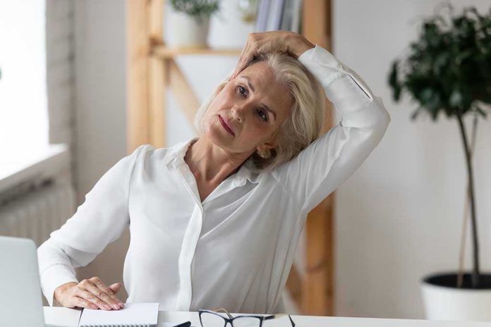 Woman stretching neck at a desk indoors