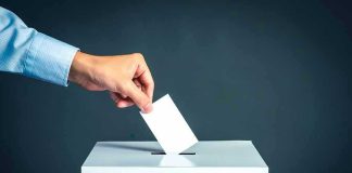 Hand placing ballot into voting box