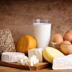 Gates-Backed Butter Sparks Nationwide Horror! Assorted dairy products including cheese, milk, and eggs on a wooden surface