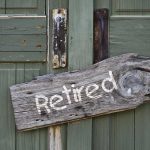 Weathered wooden sign reading 'Retired' hanging on a green door