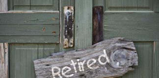 Weathered wooden sign reading 'Retired' hanging on a green door