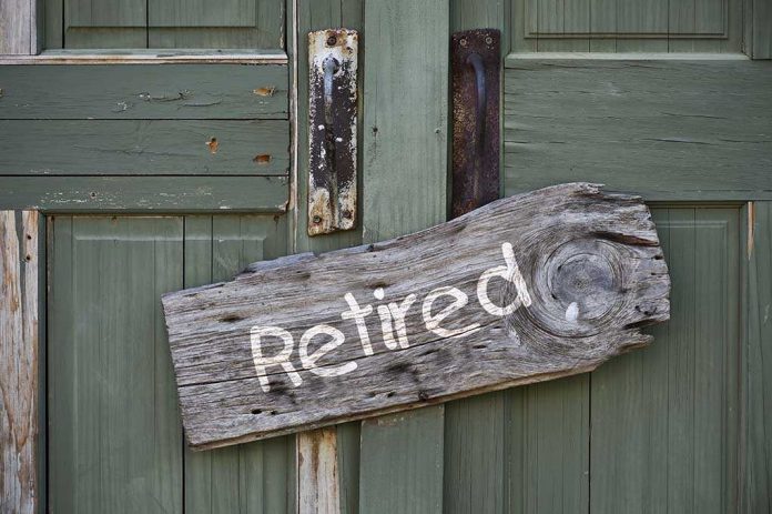 Weathered wooden sign reading 'Retired' hanging on a green door