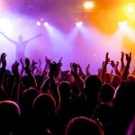 Fake Celebrity INFILTRATES Vegas Nightclub Crowd at a concert with raised hands and colorful stage lights