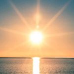 A serene sunrise over a calm ocean with vibrant colors in the sky