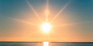 A serene sunrise over a calm ocean with vibrant colors in the sky