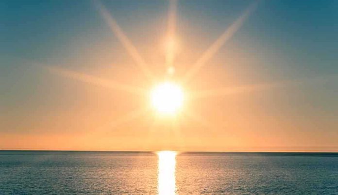 A serene sunrise over a calm ocean with vibrant colors in the sky