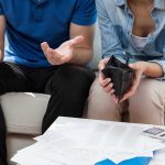 Couple looks worried with empty wallet and bills