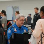 TSA agent checks passengers documents at airport security.