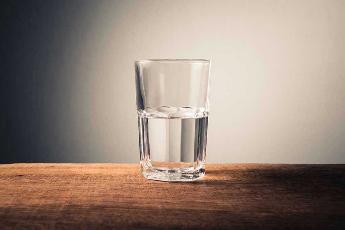 Glass of water half full on table.