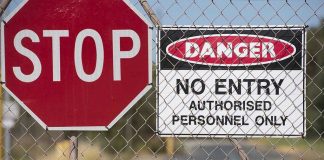 Stop and Danger signs on a chain-link fence.