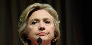 Woman in red jacket speaks into two microphones.