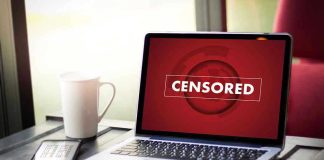 Laptop screen displaying CENSORED beside coffee and phone