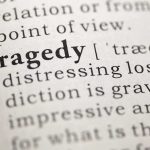 Close-up of the word Tragedy in a dictionary with its definition