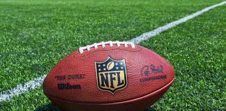 An NFL football resting on a green grass field