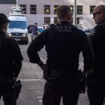 Three police officers standing on a city street.