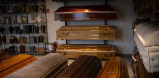 Wooden coffins and urns displayed in a showroom.