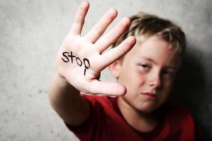 A child holding up a hand with the word stop written on it