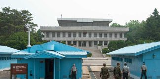 Military personnel standing near blue buildings at a border crossing