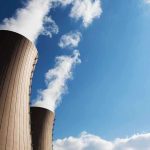Cooling towers of a nuclear power plant emitting steam against a blue sky