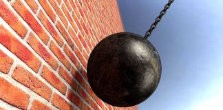A wrecking ball suspended near a brick wall, suggesting demolition activity