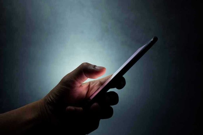 Hand holding a smartphone in the dark.