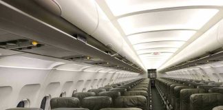 Empty airplane cabin with rows of green seats.