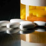 White pills beside an orange pill bottle