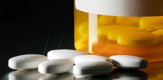 White pills beside an orange pill bottle