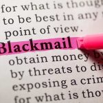 Close-up of a dictionary page with the word blackmail highlighted in pink