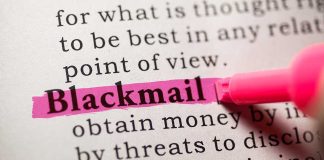 Close-up of a dictionary page with the word blackmail highlighted in pink