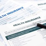 Close-up of health insurance application forms with a pen
