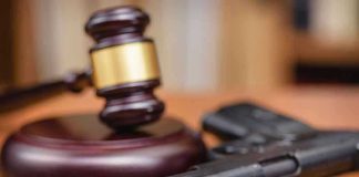 Gavel and handgun on a wooden surface.