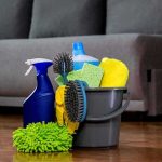 A bucket filled with various cleaning supplies including sponges, brushes, and spray bottles