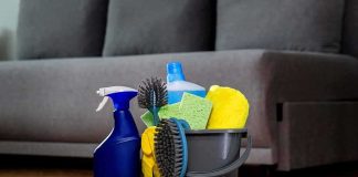 A bucket filled with various cleaning supplies including sponges, brushes, and spray bottles