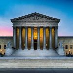 Supreme Court building with illuminated pillars and steps.