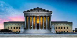 Supreme Court building with illuminated pillars and steps.