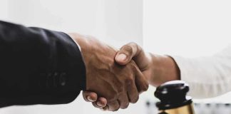 Handshaking near a gavel on desk.