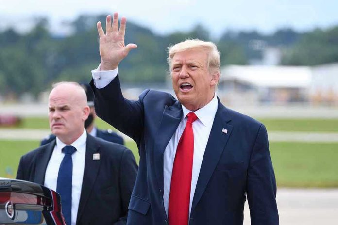 Man in suit waving while another man stands nearby.