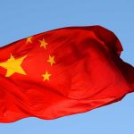 Chinese flag waving against a clear blue sky