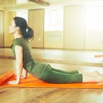 Woman practicing yoga on an orange mat in a bright studio